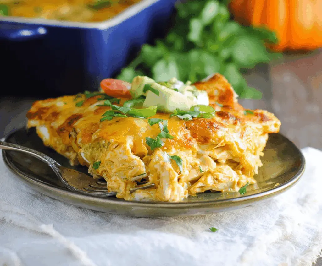 Creamy pumpkin chicken enchiladas topped with melted cheese and fresh cilantro, served on a white plate for a flavorful fall-inspired Mexican dish.