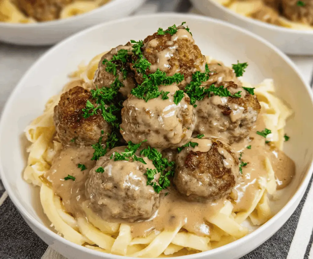 Creamy Swedish meatballs cooked in a slow cooker served with gravy and mashed potatoes, perfect for a comforting family meal.