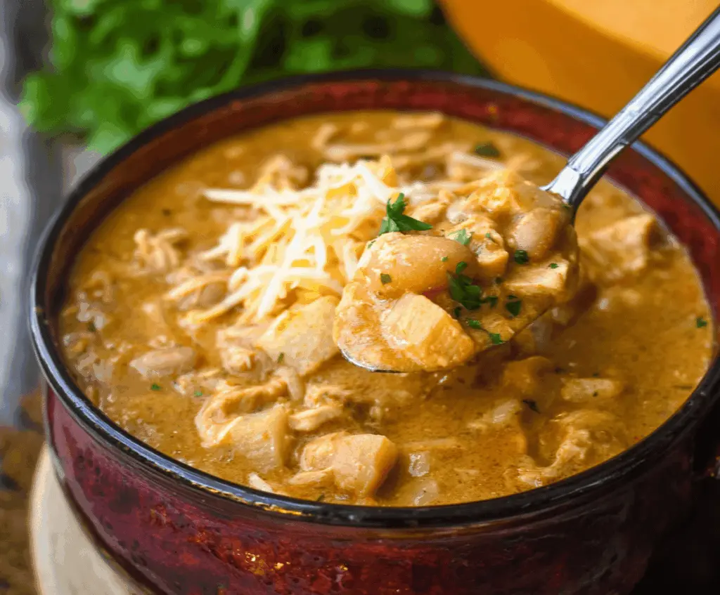 Creamy white cheddar apple chicken chili in a bowl topped with fresh herbs and diced apples, perfect for cozy meals