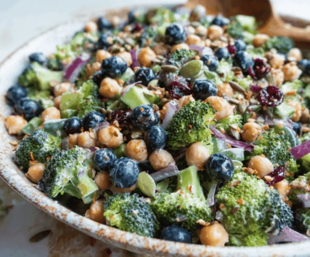 Colorful broccoli blueberry salad with chickpeas in a bowl, featuring fresh vegetables and vibrant blueberries for a healthy, delicious meal.