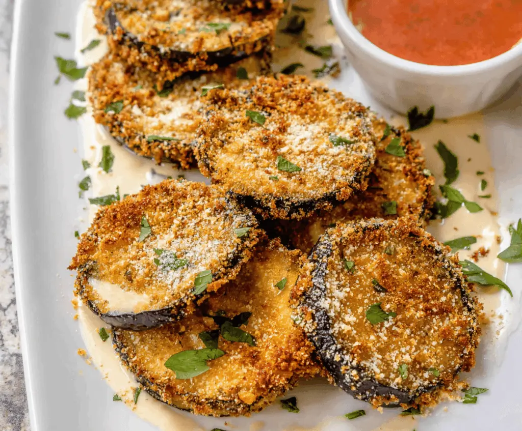 Golden crispy fried eggplant slices served on a plate, showcasing a delicious and savory vegetarian appetizer or side dish.