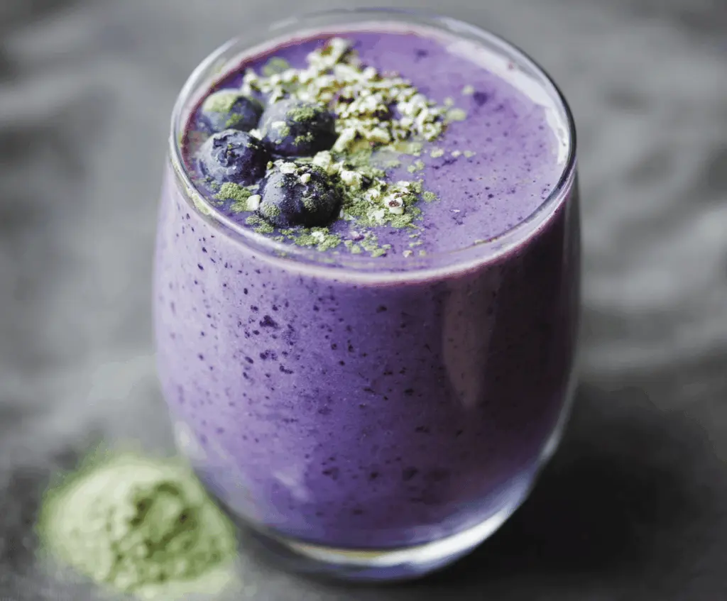 Creamy Wild Blueberry Vanilla Matcha Smoothie in a glass garnished with fresh blueberries and mint leaves
