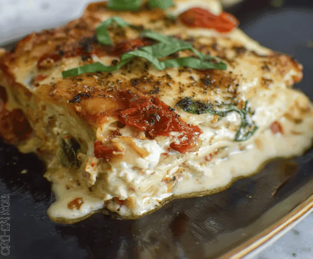 Delicious homemade sun dried tomato lasagna with melted cheese and fresh basil layers.